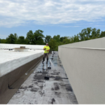 Technician cleaning flat roof membrane before commercial roof inspection checklist walkover