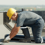 Professional roofer installing waterproof membrane during emergency roof repair on commercial building, preventing future leaks.