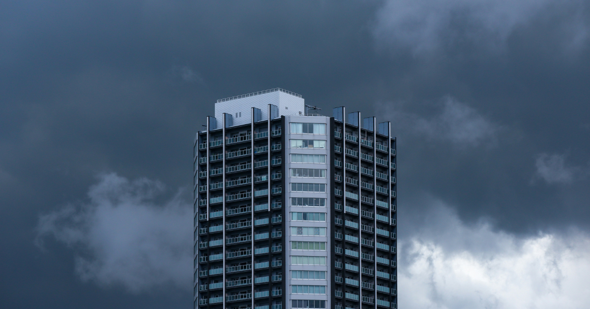 Commercial high-rise building faces threatening storm clouds highlighting the need for emergency roof damage inspections after severe weather