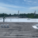 Reflective vs non-reflective roofing comparison: Contractor applying white coating to commercial roof for energy efficiency.