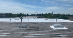 Reflective vs non-reflective roofing comparison: Contractor applying white coating to commercial roof for energy efficiency.