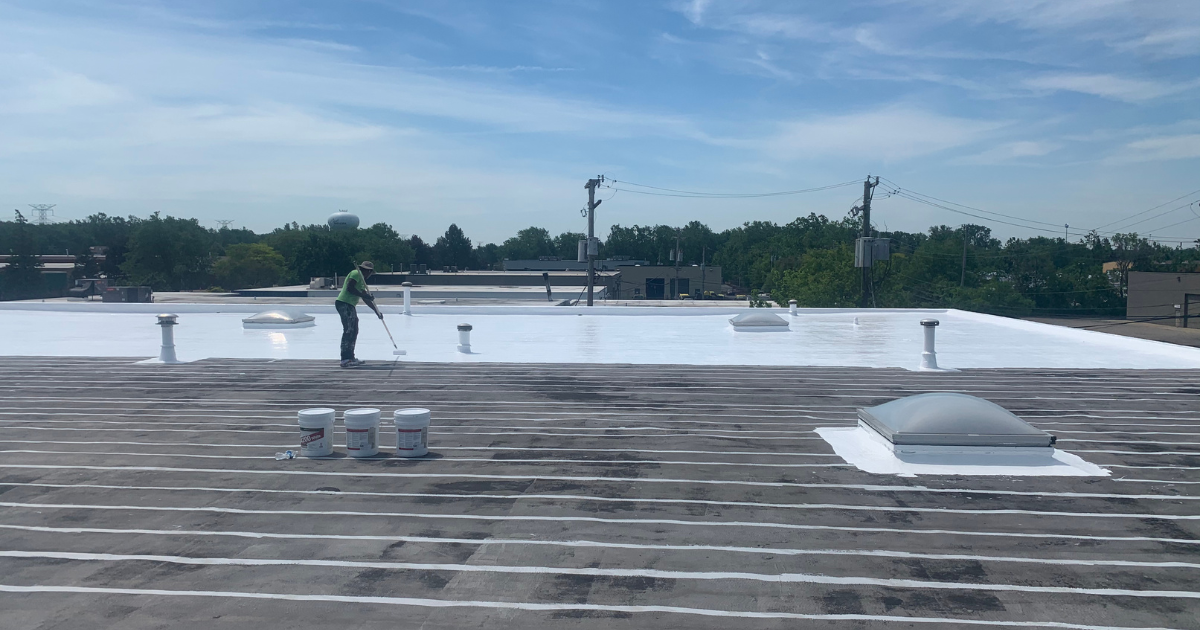 Reflective vs non-reflective roofing comparison: Contractor applying white coating to commercial roof for energy efficiency.