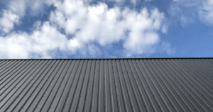 Commercial metal roofing installation featuring corrugated steel panels under blue sky, highlighting durability and modern aesthetics.