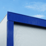 Modern industrial warehouse with blue metal roofing and white walls - durable industrial roofing solutions for large facilities