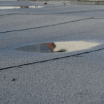 Ponding water on flat roof causing drainage problems in Detroit.