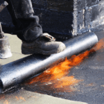 Technician applying modified bitumen roofing membrane on Detroit commercial roof