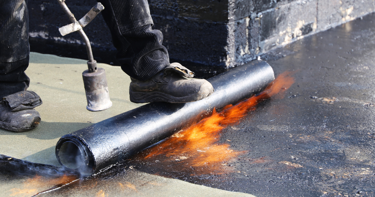 Technician applying modified bitumen roofing membrane on Detroit commercial roof