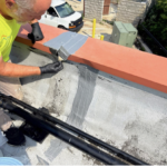 Technician sealing roof penetration during commercial roof maintenance visitroof maintenance on a Detroit flat roof