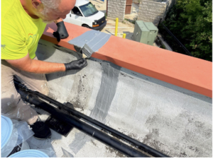 Technician sealing roof penetration during commercial roof maintenance visitroof maintenance on a Detroit flat roof