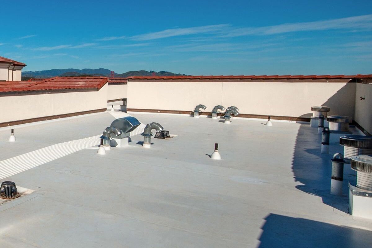 White silicone coating applied over commercial flat roof with ventilation penetrations sealed, Michigan.